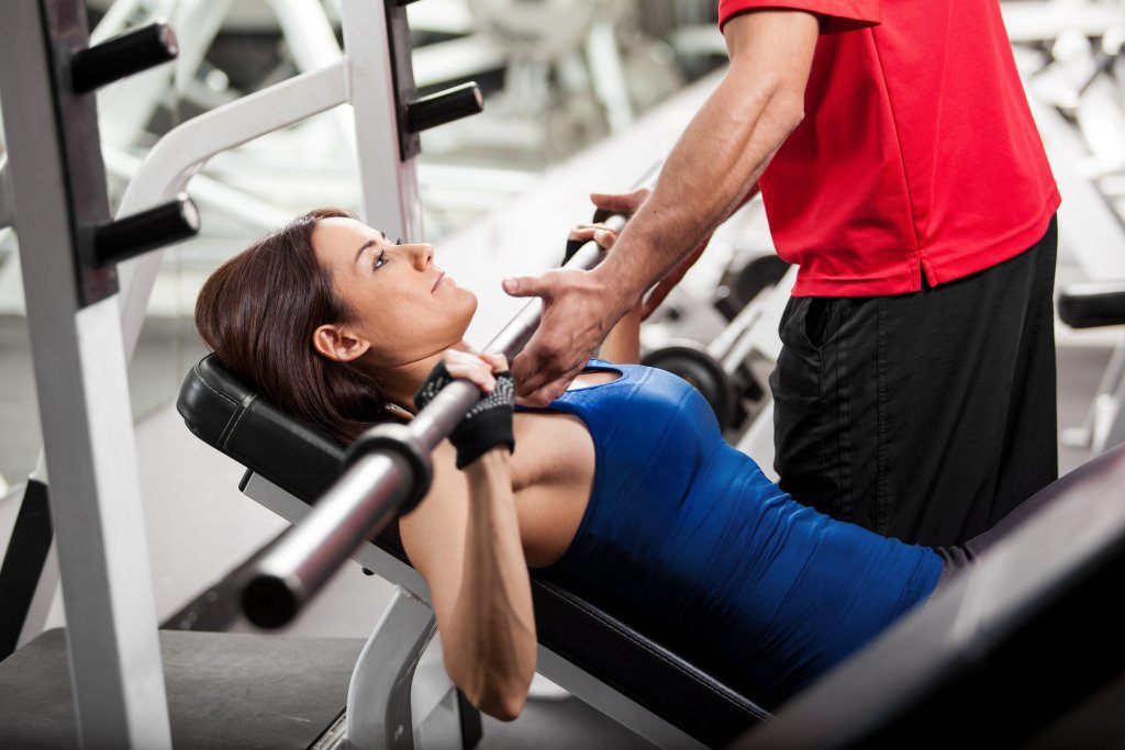 Personal Trainer Helping A Woman In A Gym